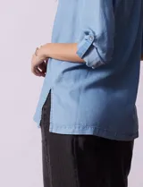 Blusa de lyocell color azul claro, con cuello camisero, escote en V con tapeta de botones y mangas largas con presilla para regular el largo.