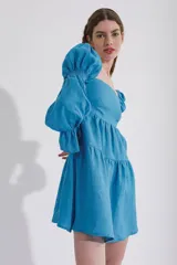 Vestido corto blanco de lino, con escote recto, mangas abullonadas 3/4 con elástico y falda con volado.