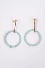 Caravanas colgantes con diseño circular, compuestas por un aro forrado en hilo color turquesa y una pieza superior metálica dorada con textura rugosa.