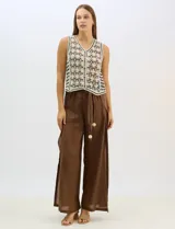Chaleco de tejido crochet con diseño calado de motivos florales y geométricos. Presenta escote en V, cierre frontal con botones y detalles de vivos a contraste en color negro en sisas, escote y ruedo.