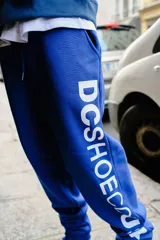 Pantalón de jogging azul con cordón ajustable en la cintura y gran estampado vertical de la marca en la pierna izquierda.