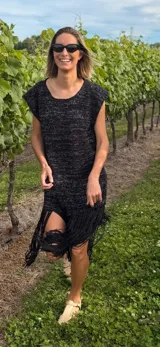 Vestido corto tejido en lurex negro con detalles en blanco, de corte holgado, mangas cortas y flecos en el ruedo.