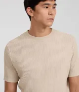 Remera de hombre color beige, corte slim fit, cuello redondo y manga corta. Tejido de punto acanalado texturizado.