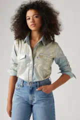 Camisa de estilo western con acabado metalizado brillante en tono azul claro y plateado. Presenta cuello clásico, cierre frontal con botones a presión, dos bolsillos en el pecho con solapa y mangas largas con puños abotonados.