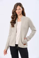 Campera tejida de punto color beige, con cuello alto, cierre frontal con tirador circular y bolsillos laterales. Presenta detalles de rib en puños y ruedo, además de un parche de cuero sintético en el frente.