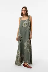 Vestido largo verde militar con estampado floral, silueta amplia, escote redondo y tirantes finos con detalle de botones.