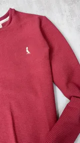 Buzo rojo de algodón texturizado, cuello redondo y mangas largas.