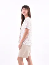 Remera de manga corta color beige con estampado de bananas en tonos amarillo, naranja y rosado.