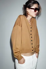 Chaqueta de punto color tostado con cuello en pico, manga larga con puños y cierre frontal con botones.