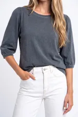 Remera de algodón lavado gris oscuro, con cuello redondo y mangas cortas abullonadas estilo globo con puños fruncidos.