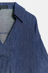 Camisa de lino azul, con cuello solapa, escote en V y mangas por debajo del codo.