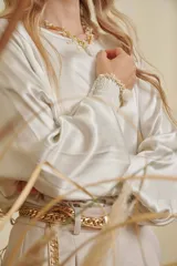 Blusa de satén color champagne con cuello a la base, mangas anchas y puños elásticos con detalle bordado.