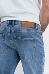 Pantalón de jean corte regular, color azul medio con efecto lavado, de tiro medio y cierre frontal con botón y cremallera.