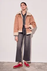 Campera gamulan color rosa con interior de piel sintética color crema, cierre frontal con cremallera y hebillas en el cuello. Corte oversize.