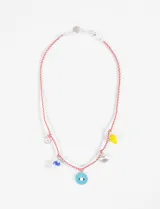 Collar con cordón rojo y cadena plateada con cierre de mosquetón. Incluye charms colgantes: ojo turco, hongo azul, concha plateada y limón amarillo.