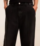 Pantalon de jean negro de corte super baggy, con tiro alto, frisos decorativos y efecto desgastado. Posee cintura con trabillas, cierre frontal tradicional y bolsillos laterales.