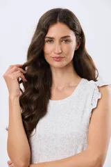 Musculosa blanca con estampado floreado sutil y volados en los hombros, de corte recto.