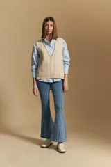 Chaleco tejido color azul, con escote en V, cierre frontal con botones y diseño de líneas verticales en relieve. Presenta terminaciones acanaladas en el ruedo y un borde ondulado en el escote.