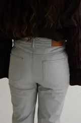 Pantalón cropped de tiro medio con acabado engomado, corte recto y bolsillos laterales. Presenta cierre frontal con botón y costuras a tono.