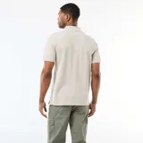 Remera polo color beige, de manga corta, con cuello y puños ribeteados en color blanco y cierre frontal de tres botones.