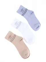 Pack de tres pares de medias tobilleras de algodón, colores blanco, celeste claro y beige. Todas presentan el logo Umbro y franjas decorativas en el borde superior.