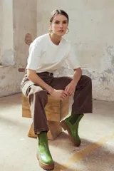 Bota tipo chelsea con suela track de goma en color marrón y capellada de cuero negro. Presenta elásticos laterales y tirador trasero.
