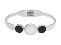Pulsera rígida de acero plateado con tres apliques circulares: dos de ónix negro y uno central de nácar blanco con números romanos grabados.