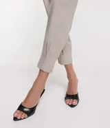 Pantalón negro de lino, corte carrot, con cintura ancha y pliegues en el bajo.