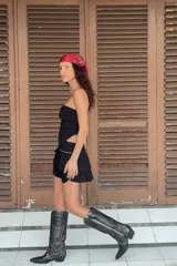 Falda pantalón corta de tiro medio, color negro, con cintura elástica en la espalda. Presenta detalle de tachas metálicas en la parte delantera y diseño de volantes a tono. Incluye forro interior.