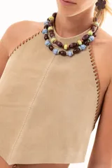 Top de gamuza color visón con escote halter y costuras decorativas con detalle de tientos de cuero en los bordes laterales.