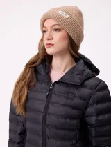 Gorro tipo beanie de punto acanalado color bordó, con etiqueta rectangular blanca con logo de la marca en el frente.