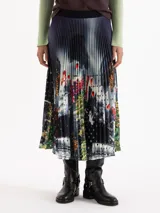 Pollera midi plisada con estampa digital artística y detalles de círculos calados. Presenta una cintura con elástico negro a la vista.