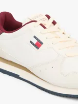 Zapatillas runner Tommy Jeans Eva de estilo urbano, confeccionadas en una combinación de cuero blanco, textil y material sintético. Presentan detalles en color bordó en el talón y el interior, entresuela con franja marrón y suela dentada azul. Cuentan con el logo de Tommy Jeans bordado en el lateral.