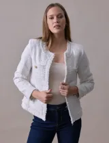 Chaqueta Nanette de tejido tweed color blanco, con escote mao, abertura central y bolsillos delanteros. Presenta apliques de botones perlados en los puños y terminación desflecada.
