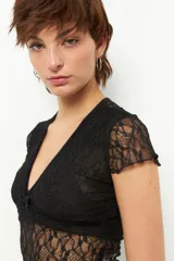 Top de encaje negro con escote en V y tiras de terciopelo. Es de manga corta y corte ajustado.