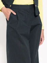 Pantalón de vestir negro con finas rayas verticales blancas, estilo sastrero con pinzas y corte palazzo.
