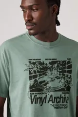 Remera verde militar de corte relajado, manga corta y cuello redondo, con estampa frontal en negro con temática de vinilos y estilo vintage.