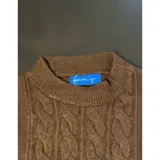 Buzo de punto blanco de manga larga con diseño trenzado y cuello redondo.