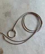 Gargantilla con cordón gris y dije circular de plata.