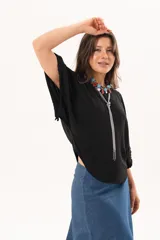 Blusa de silueta relajada y caída fluida, color negro, con escote redondo y mangas amplias.