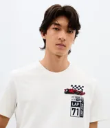 Remera de algodón color blanco con cuello redondo y mangas cortas. Presenta una estampa en la espalda con diseño de un auto de Fórmula 1, bandera a cuadros y la inscripción Grand Prix Legend en tonos rojos y azules.