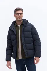 Campera puffer con capucha integrada, cierre frontal cubierto y bolsillos laterales. Confeccionada en nylon, presenta un diseño acolchado y funcional ideal para climas fríos.