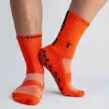 Medias deportivas de caña media color fucsia, con suela antideslizante de puntos negros y logo de la marca estampado en la parte superior.