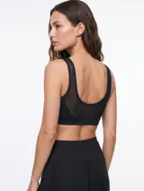 Top deportivo negro con escote redondo y detalle de malla en el centro del pecho, de diseño ajustado y tirantes anchos.