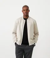 Chaqueta tipo bomber para hombre, de color beige, con cierre frontal de cremallera, cuello redondo acanalado y puños y ruedo elásticos. Presenta un diseño minimalista y liso.