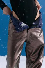 Pantalón de jean estilo oversize de tiro medio-bajo, confeccionado en denim 100% algodón. Presenta un acabado metalizado en tono peltre con efecto lavado violeta, logrando un brillo irregular y profundo. Incluye avíos metálicos personalizados y badana de PU en la parte posterior.