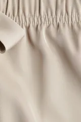 Short de sarga de tiro alto, color beige, con corte holgado, cintura elástica y lazo decorativo frontal. Cuenta con bolsillos laterales discretos.