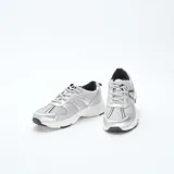 Zapatillas de running color gris metalizado con paneles de malla transpirable, cordones al tono y suela blanca con detalles en negro.