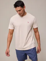 Remera de mangas cortas color beige con logo de pájaro bordado en rojo en el pecho.