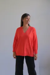 Sweater de punto color naranja, con cuello en V, manga larga y diseño holgado con tajos laterales en el ruedo.